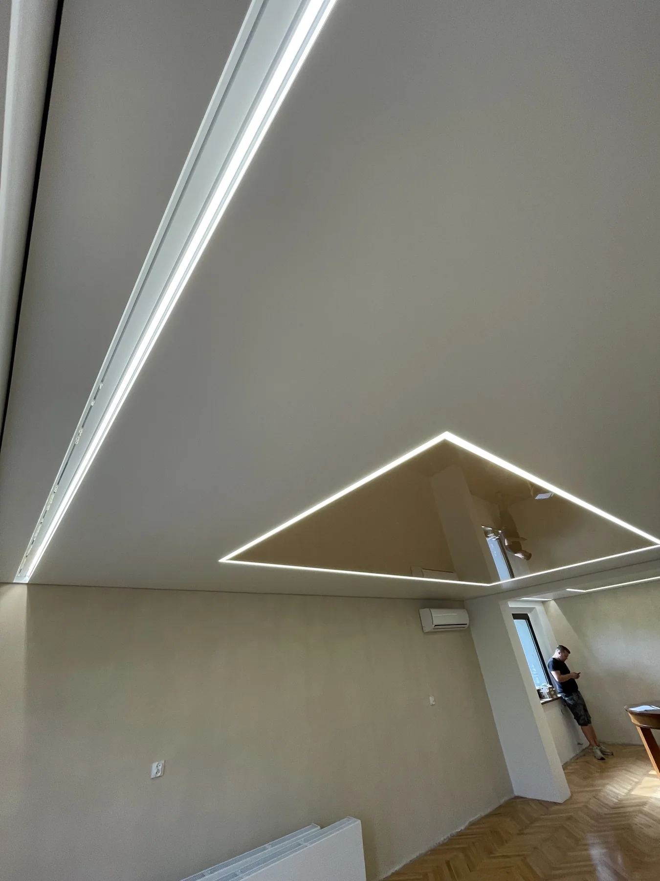 Jasny sufit napinany z długą linią LED i geometrycznie podświetloną wstawką