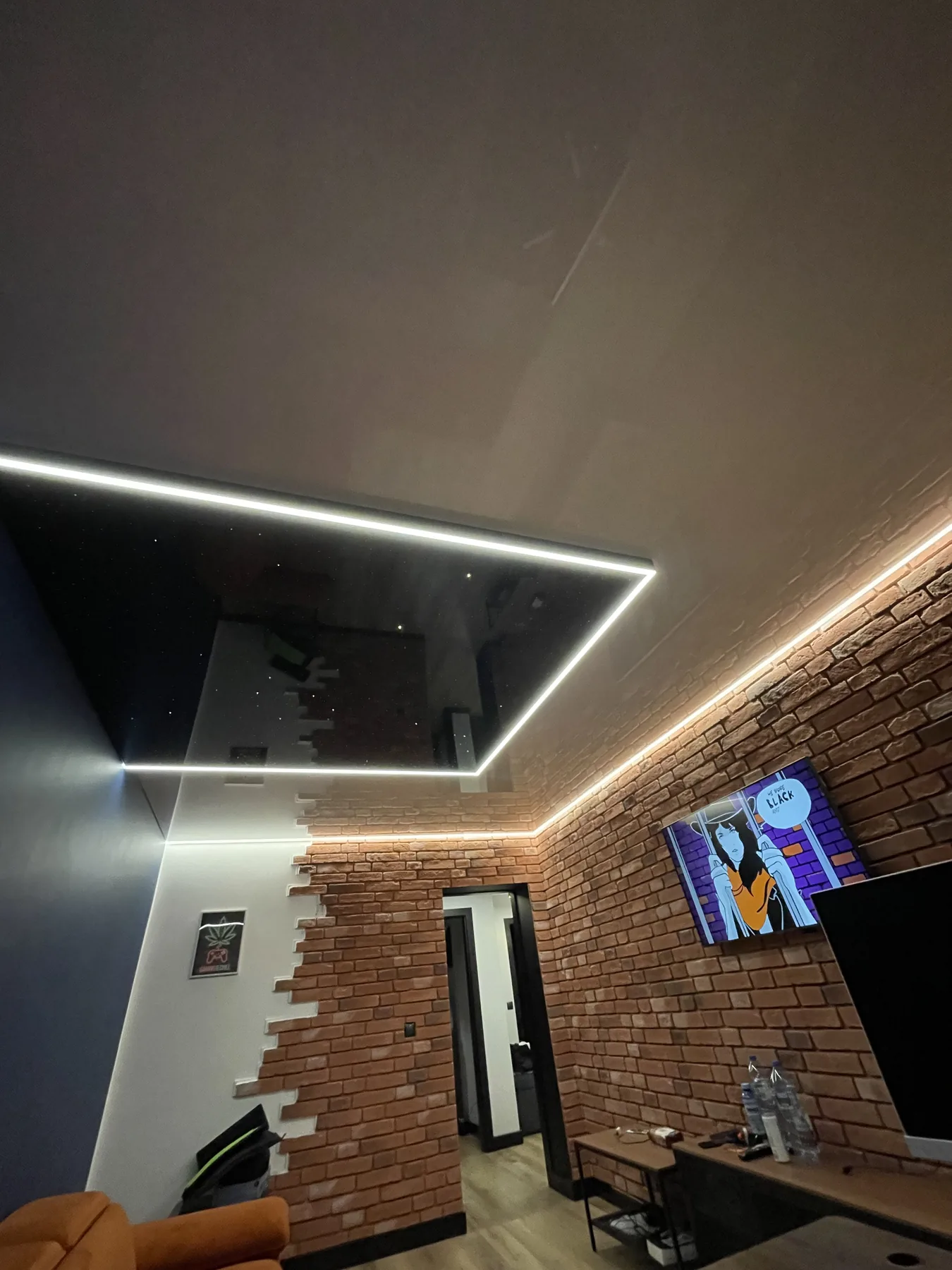 Ciemny lustrzany sufit napinany z linią LED nad salonem z ceglaną ścianą