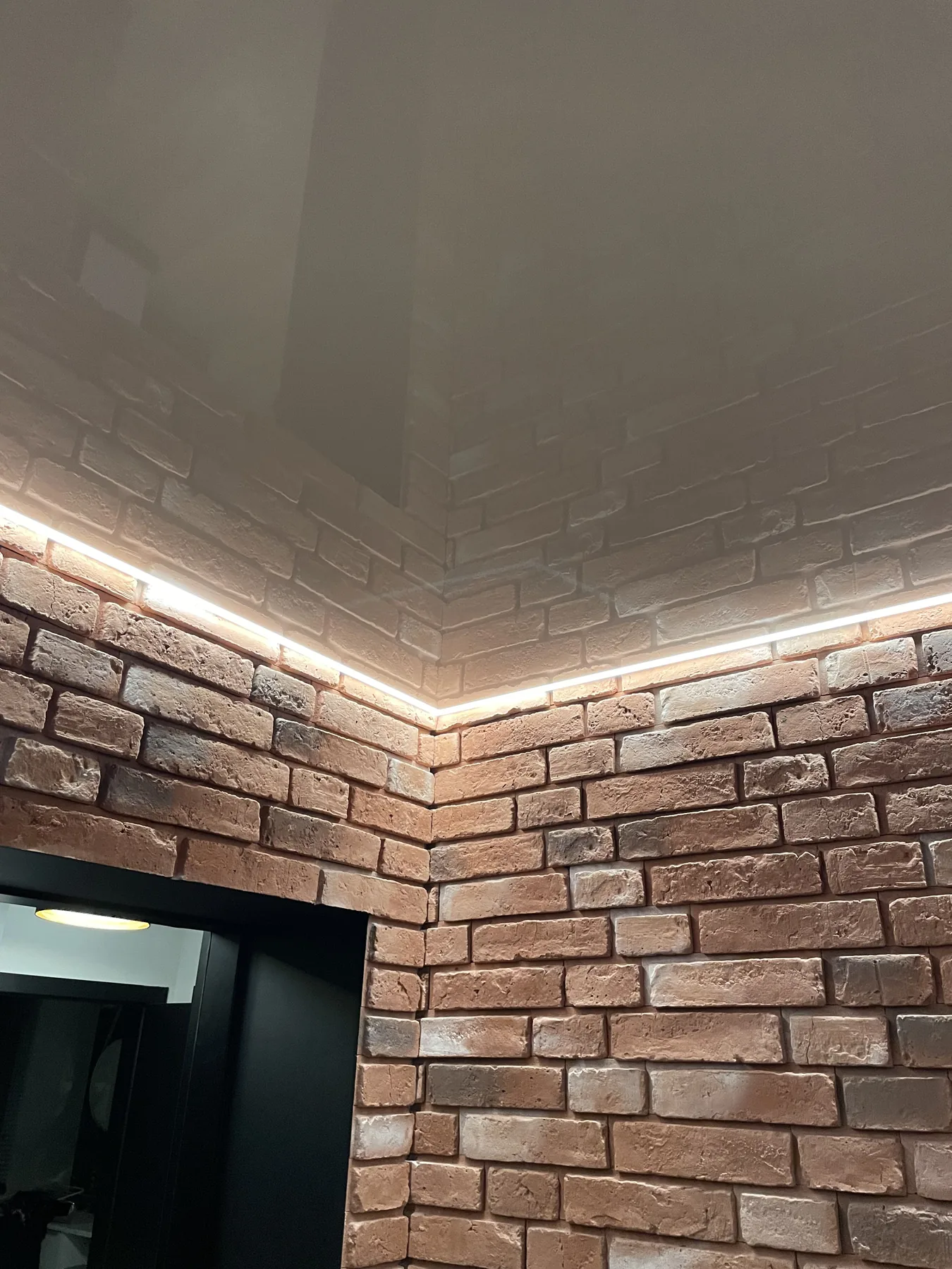 Detal liniowego oświetlenia LED na styku sufitu i ceglanej ściany