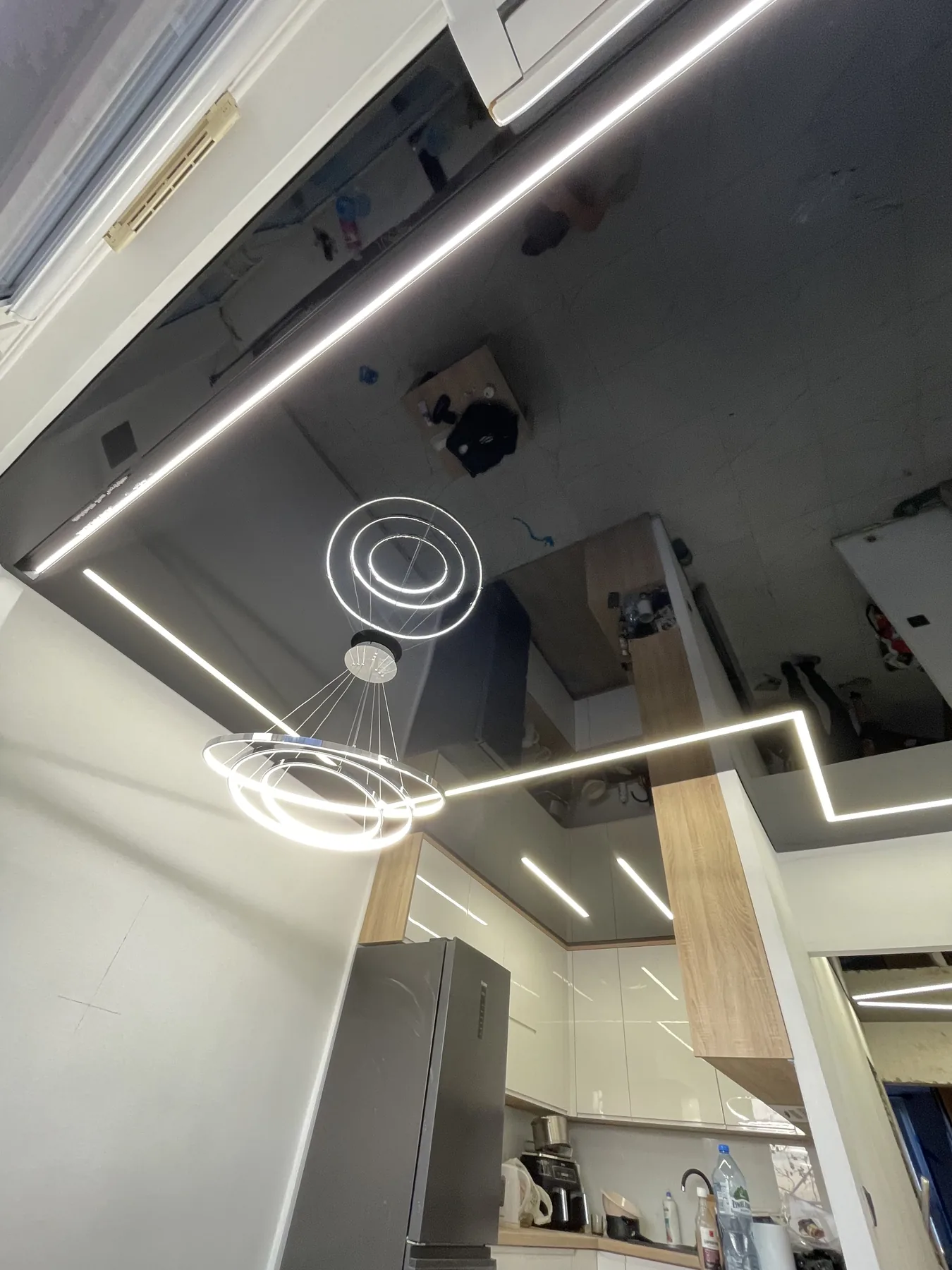 Czarny lustrzany sufit napinany nad kuchnią z liniami LED i wiszącymi okrągłymi lampami